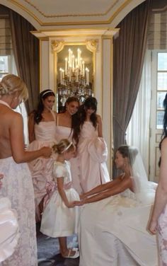 a group of women standing around each other in front of a bride and her maids