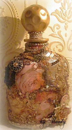 an ornate bottle is adorned with gold and pink flowers on a white wallpapered background