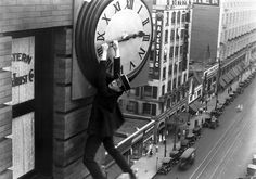 a man climbing up the side of a building with a large clock on it's face