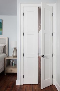 an open white door in a bedroom next to a bed