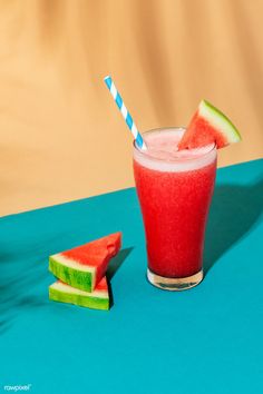 a watermelon drink with a blue and white striped straw next to slices of watermelon