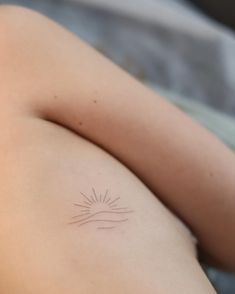 a woman's arm with a small sun tattoo on her left shoulder and the other arm behind her