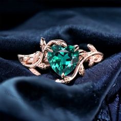 a green heart shaped ring sitting on top of a black cloth