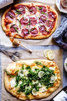 two pizzas sitting on top of a table covered in cheese and veggies