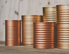 several stacks of gold colored tins sitting on top of a wooden table