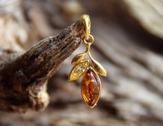 - Beautiful and delicate pendant with two stones of different colors of Baltic Amber carved in the shape of a marquise composed in a floral design, wrapped in gold; - Pendant made of 925 gold-plated silver 14k; - Made with certified Natural Amber of the Baltic Sea, fished on the south coast by our seekers and processed in our laboratory; - Handmade through traditional craft techniques, the original may differ slightly from the images; - Amber size is 14 x 6 mm and 8 x 3 mm; - Length 32 mm, width Delicate Pendant, Craft Techniques, Modern Style Design, Photo P, Amber Ring, Gold Leaves, Natural Amber, Baltic Sea, Traditional Crafts