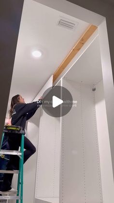 a woman is on a ladder painting the ceiling