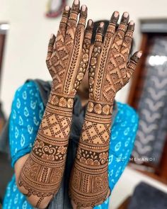 a woman holding her hands up to show the intricate design on her hendi, which is