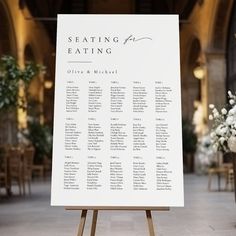 seating chart on easel in large hall with floral centerpieces and white flowers