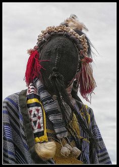 a person with dreadlocks on their head wearing a striped jacket and carrying a bag