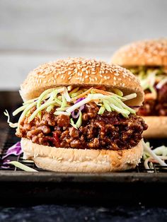 two sloppy joe sandwiches sitting on top of a black tray