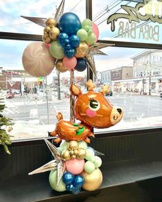 a balloon sculpture in front of a window with balloons and stars hanging from it's sides