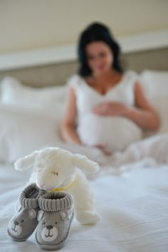 a woman laying in bed with a stuffed animal and slippers on her feet,