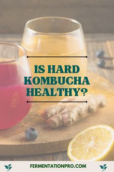 a wooden cutting board topped with lemons and blueberries next to a glass of kombucha