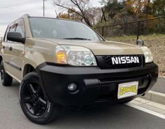 a tan nissan suv is parked on the street