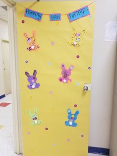 a door decorated with paper cut outs and bunting on the side, saying happy easter