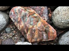 a rock sitting on top of a pile of rocks covered in dirt and gravel next to other rocks