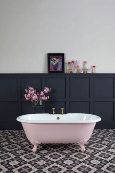 a pink bathtub sitting on top of a black and white floor next to a wall