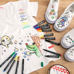 children's clothing and crayons are laid out on a wooden floor with shoes