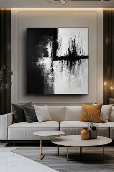 a large black and white painting hanging on the wall above a couch in a living room