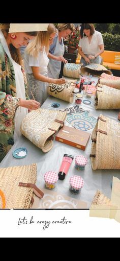 people standing around a table with bags and purses on it's tables are lined up