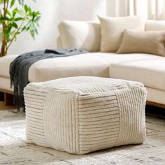 a living room with a large white couch and ottoman on the floor next to a potted plant