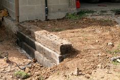 a pile of wood sitting on top of a dirt field next to a garage door