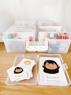 two plastic containers filled with personalized items on top of a wooden table in front of a white wall