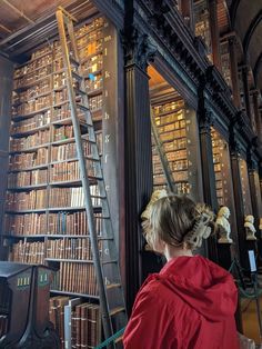 a woman sitting in front of a book shelf filled with books next to a stair case