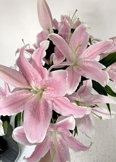 a vase filled with pink flowers sitting on top of a white countertop next to a mirror