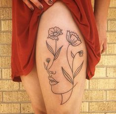 a woman's thigh with flowers on it and a face drawn in the middle