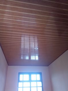 an empty room with a window and wooden slats on the ceiling