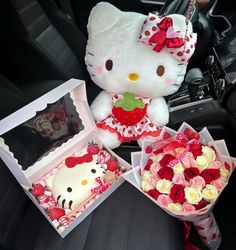 hello kitty sitting in the back seat of a car next to two boxes of roses