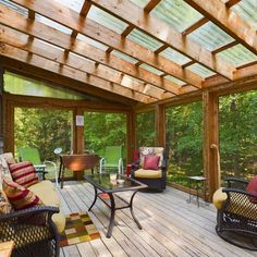 a covered porch with chairs and tables in the middle of it, surrounded by trees