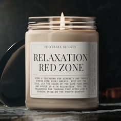 a candle sitting on top of a table next to a black container with a label that says relaxation red zone