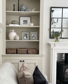 a living room filled with lots of white furniture and shelves next to a fire place