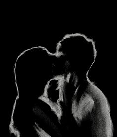 a black and white photo of two people kissing in the dark, with one person's head on his shoulder