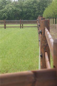 the fence is made of wood and has metal bars on it, along with grass