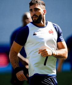 a man with a beard wearing a white and blue shirt is holding a frisbee