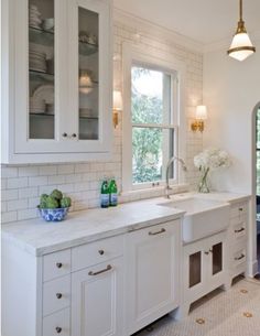 a large kitchen with white cabinets and marble counter tops, along with an arched doorway leading to the outside