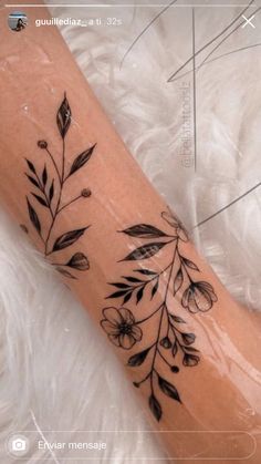 a black and white photo of a flower tattoo on the left arm, with leaves coming out of it