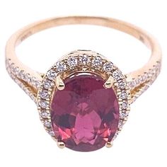 an oval shaped pink tourmaline surrounded by white and yellow diamonds in a gold ring