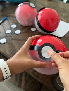 a person holding a poke ball in front of some other items on a wooden table