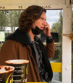 a woman talking on a cell phone while sitting at a table with drinks and ice cream