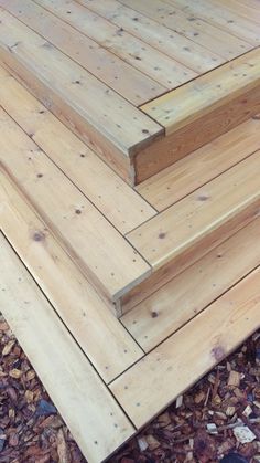 three wooden steps sitting on top of a pile of wood flooring next to leaves