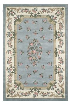 a blue rug with flowers and leaves on it's border, in the middle of a