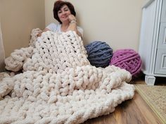 a woman is sitting on the floor under a large crocheted blanket with balls