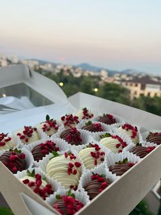 a box filled with chocolate covered strawberries on top of a lush green field next to a city