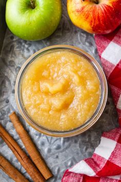 apples, cinnamon sticks and an apple in a glass jar on a checkered table cloth