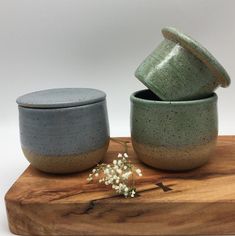 two ceramic bowls sitting on top of a wooden board